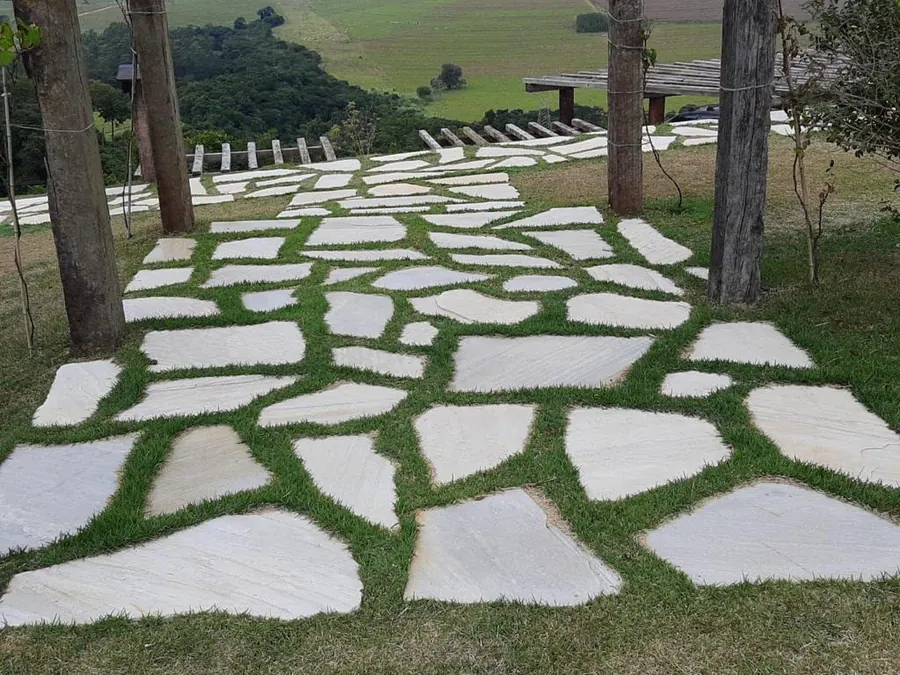 Caminho de pedras irregulares no jardim, entre a grama