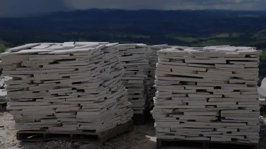 Pilhas de placas de Pedra São Tomé empilhadas na pedreira, com vista da serra