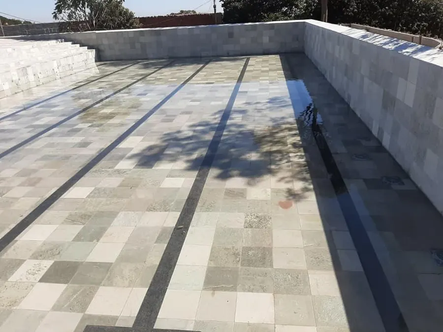 Piscina grande em obra sendo revestida com pedra